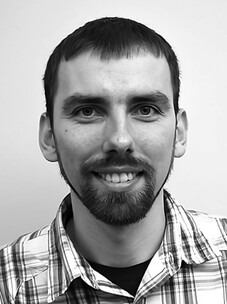 Herr Surowka in Schwarz-Weiß, mit kariertem Hemd und Bart.